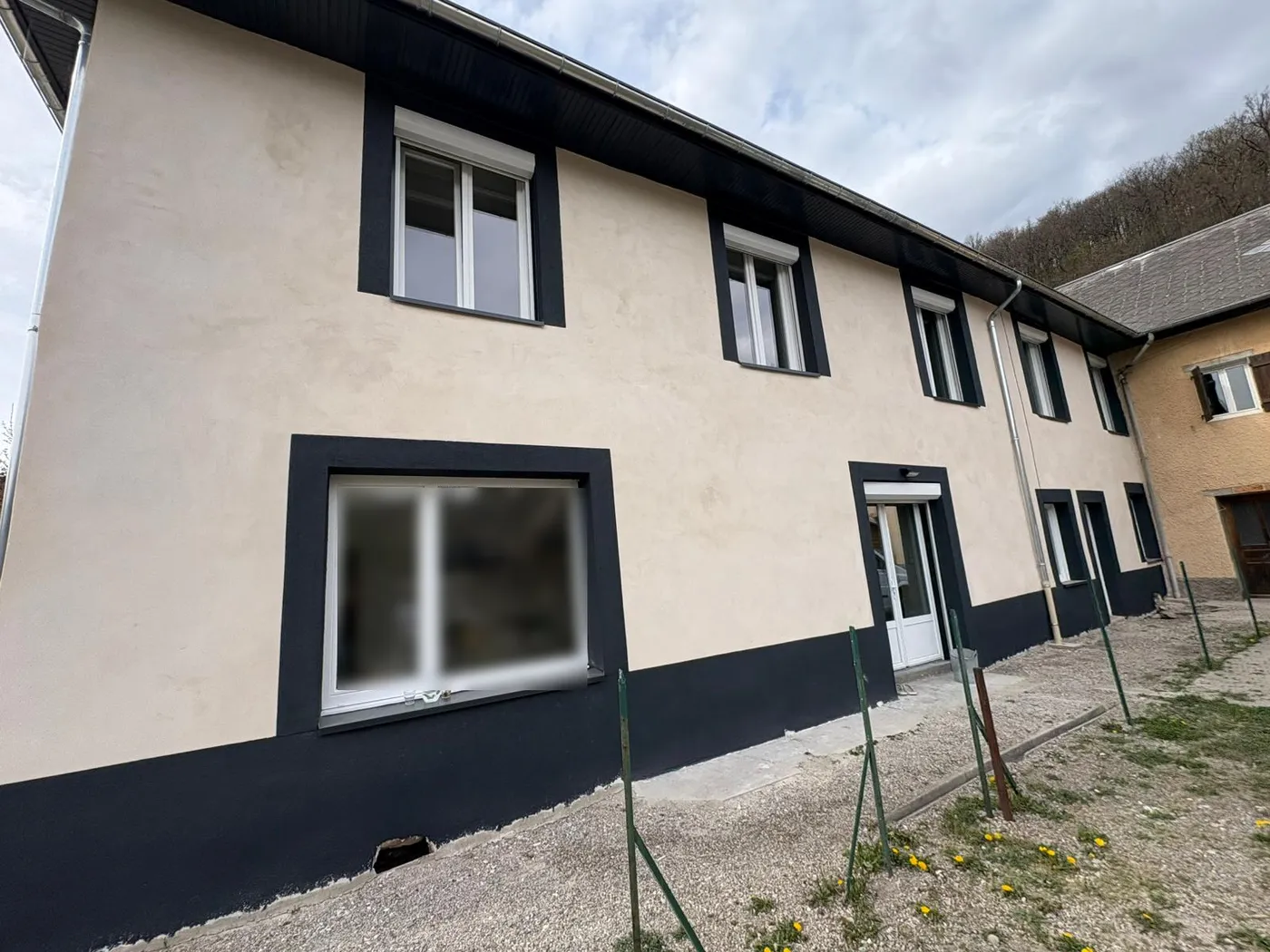 Petit immeuble à la façade enduite et aux encadrements sombres